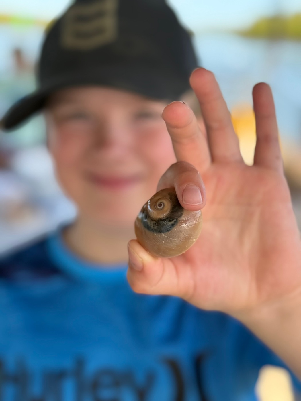 Boy holding up a moon snail shell on the tiki boat
