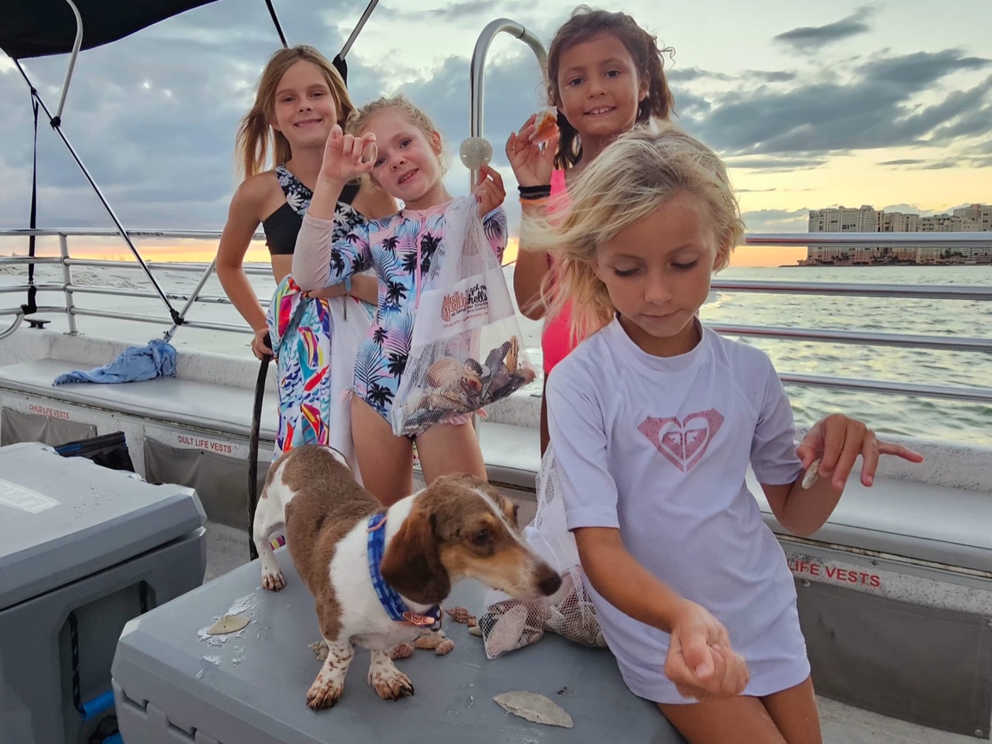 Family with dog showing off shells on the pontoon boat at sunset