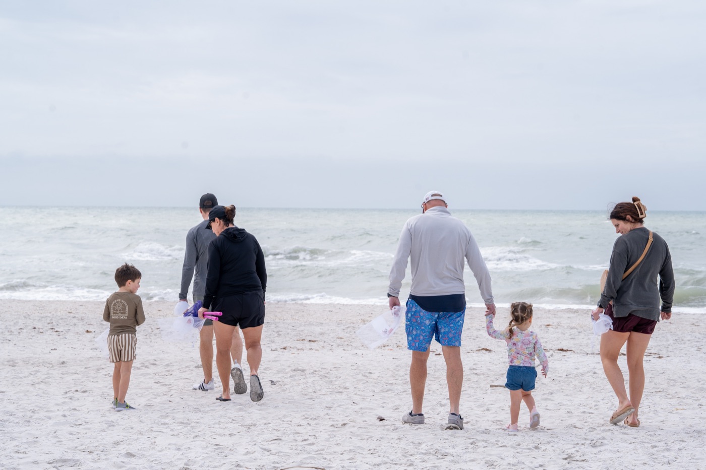 Multigenerational family shelling on a shell-covered beach in Marco Island