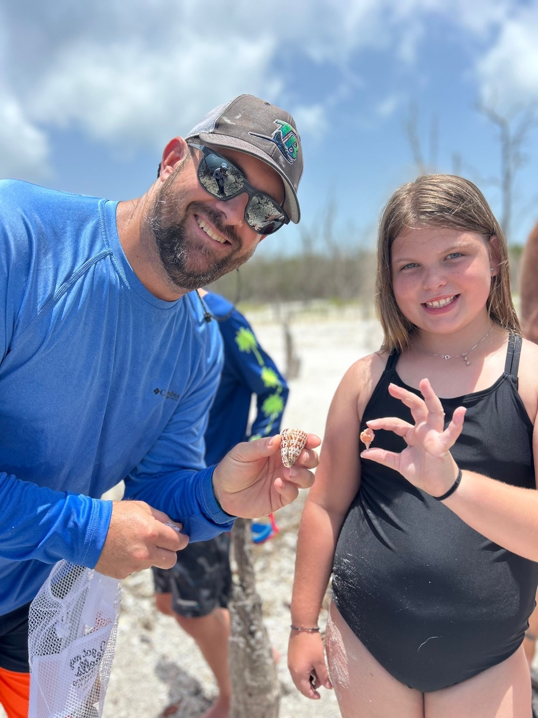 Father and daughter proudly displaying their shell finds